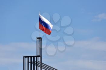 Flag of Russia against the blue sky with wind.