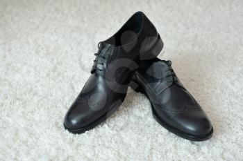 Men's stylish shoes on a white carpet.