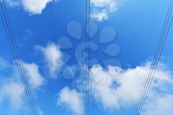 Large power line wires against the blue sky with clouds.