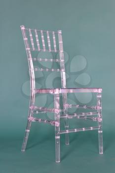 Transparent plastic chair on a green background in a photo studio.