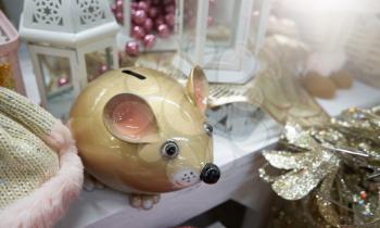 Sale of a piggy bank in the form of a mouse in a store on a shelf with decor and gifts for Christmas or New Year