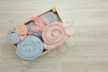 Wooden box with warm knitted plaids of pink and blue color. Close up.