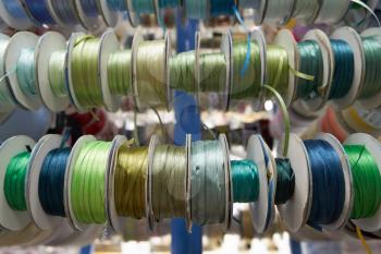 Colored ribbons for needlework in coils on the shelf in store.