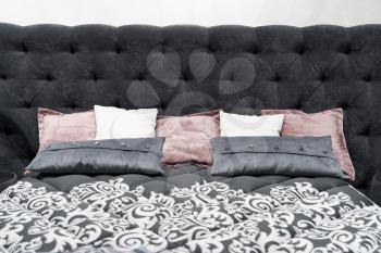 Bed with a large gray soft headboard and pillows.