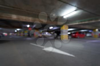 Blurred background underground parking for cars with arrows in the shopping center.