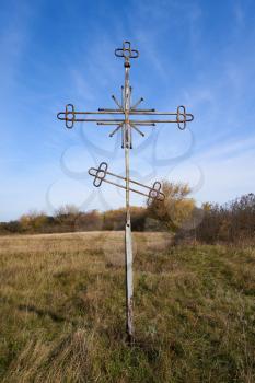 Cross next to an abandoned church in the middle of a field