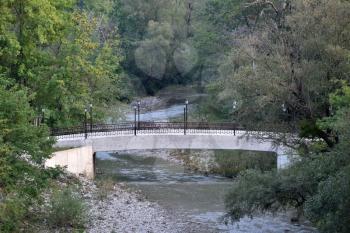 Beautiful and durable bridge with lanterns for lighting. Bridge over a small mountain river in a mountain gorge, near the town of Gelendzhik