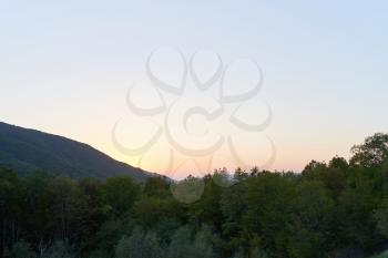 Evening landscape with mountains overgrown with trees against a sunset. Beautiful mountains around Geledzhik
