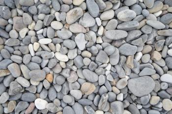 Texture of gray oval pebble stones next to the sea