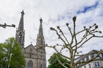 Branches of a platanus tree against the background of an evangelical church with towers in Europe. August Square, Baden Baden