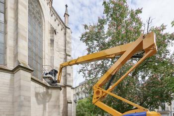 Special machine for lifting to a height. A worker makes restoration of an old building of the Evangelical Church at a high altitude