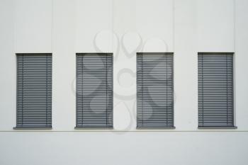 Four narrow windows with closed gray shutters on the light wall.