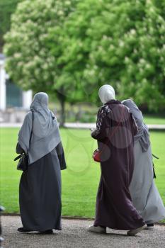 Three women refugees walking in hijabs in the European park. Germany