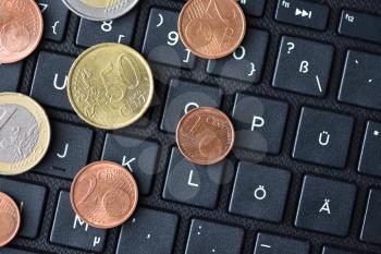 Euro coins lie on the laptop keyboard in black, close-up, symbol of working on the Internet or online payment for purchases, space for text