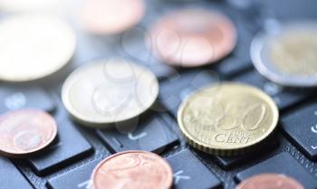 Euro coins lie on the laptop keyboard in black, close-up, symbol of working on the Internet or online payment for purchases, space for text