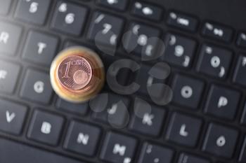 Euro coins lie in the form of a pyramid on a laptop keyboard in black, space for text