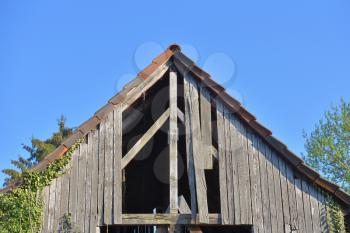 Old wooden and holey shed roof against a blue sky