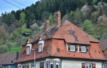 Large old tiled roof with replaced individual parts by another tile