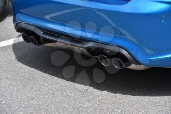 Dual exhaust pipe and blue bumper on a sports car.