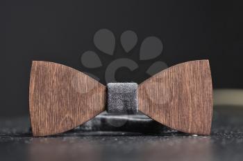 Stylish men's brown wooden bow tie with gray fabric on an iron rough surface. Accessory for brutal men, close up