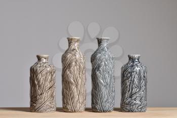 Four textured vases with leaf texture. Vases beige and gray on a wooden table. Close-up