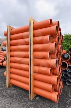 Packing of orange plastic pipes for the sewage system.