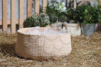 Rustic style decor, woven basket woven on dry hay against the backdrop of Easter decorations. Closeup