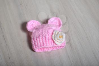 Cute children's knitted hat with ears like a mouse on a white carpet