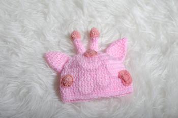 Cute children's knitted hat with ears and horns on a white carpet background