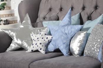 Beautiful pillows in the shape of a star of different colors lie on a sofa