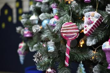 Decoration in the form of a sweet candy and a piece of cake hanging on a Christmas tree