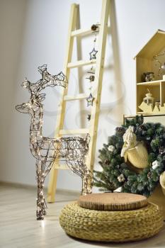 Children's playroom with wooden furniture, a house decorated for the New Year holiday with a Christmas tree, and a luminous deer from garlands.