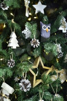 Decoration in the form of a wooden star, the shape of a spruce and an owl hanging on a Christmas tree with a snow effect