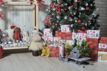 Soft toys and gifts lie under the Christmas tree in the children's room.