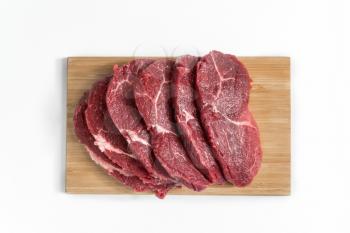 Freshness raw beef in pieces on the cutting board with white background, still life photography.