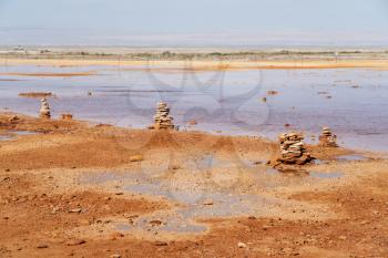 Muddy ground with spring water, with stacks of stones on one side. Photo in Qinghai, China.
