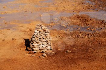 Muddy ground with spring water, with stacks of stones on one side. Photo in Qinghai, China.