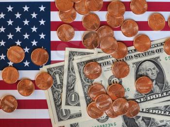 One Dollar banknotes and One Cent coins (USD) currency money over the flag of the United States