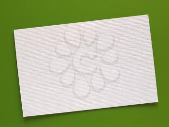 Blank paper tag label or sticker with copy space - flat lay on green desktop background