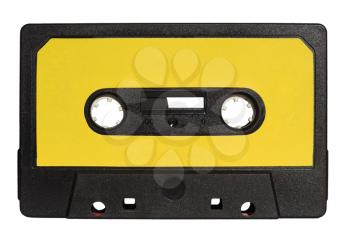 black magnetic tape cassette for analog audio music recording with yellow label isolated over white background