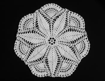 A detail of a decorated ornamental doily - over black background