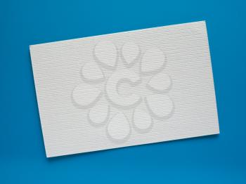 Blank paper tag label or sticker with copy space - flat lay on blue desktop background