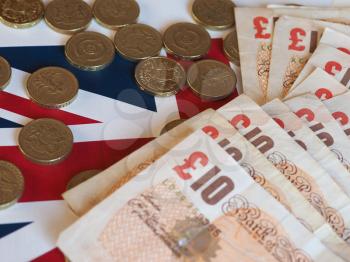 Pound coins and banknotes money (GBP), currency of United Kingdom, over the Union Jack