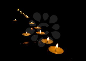 flickering flame of lit votive prayer wax candles in a church shining in the dark