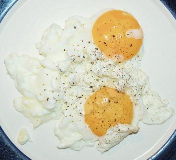 Fried eggs in a dish - sunny side up - with ground black pepper