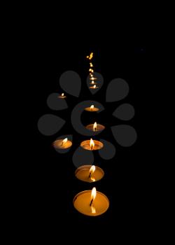 flickering flame of lit votive prayer wax candles in a church shining in the dark