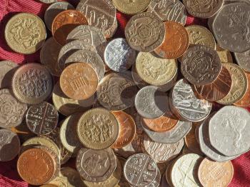 Pound coins money (GBP), currency of United Kingdom over crimson red velvet background