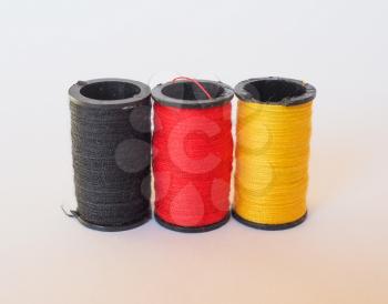 Thread spools of three different colours in the shape of the German flag