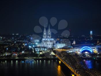 Night aerial view Koelner Dom Sankt Petrus (meaning St Peter Cathedral) gothic church and Hohenzollernbruecke (meaning Hohenzollern Bridge) crossing the river Rhein in Koeln, Germany