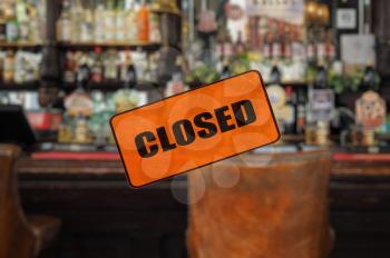 Empty pub, closed sign, focus on foreground with blurred background